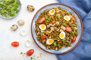Mung bean porridge with quail eggs, tomatoes and microgreen sprouts on a white concrete background. Top view, close up.