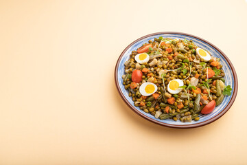 Mung bean porridge with quail eggs, tomatoes and microgreen sprouts on a pastel orange background. Side view, copy space.