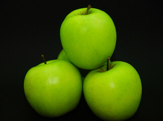 Essen-Fotografie: grüne Äpfel vor schwarzem Hintergrund.