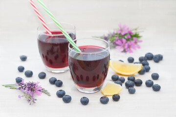 Fototapeta na wymiar Blueberries and blueberry juices in glasses with straws. Fresh homemade blueberry or aronia juice..