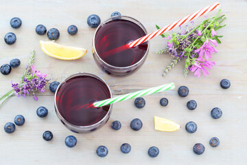 Blueberries and blueberry juice on white board. Fresh homemade blueberry or aronia juice, top view..