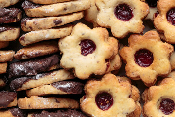 Top view of chocolate-dipped and flower shaped, with marmalade center, German Christmas cookies, baked in traditional, home-made, grandma style. Horizontal close-up.