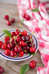 Ciliegie rosse su un piatto bianco e ciliegie fresche sparse sul tavolo