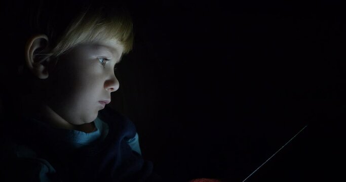 Portrait of child look at tablet screen in the dark, hidden search