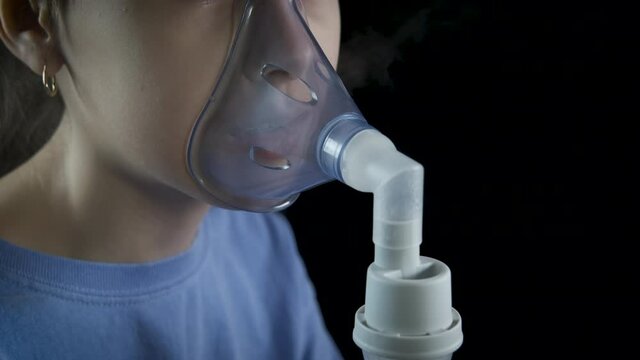 Cure with a nebulizer. The girl is breathing in a nebulizer mask.