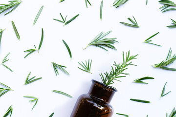 Fresh rosemary leaves with essential oil bottle on white background.