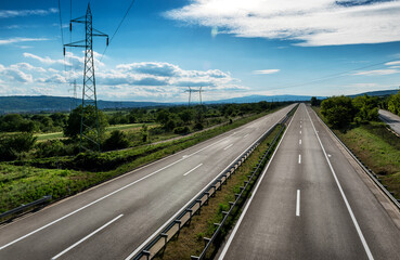 Empty silent Asphalt highway road with beautiful sky and a row of electricity pylons