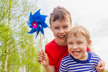 Two European boys in red and blue t-shirts with weather vents in the wind. Children jump, smile and laugh in spring or summer.
