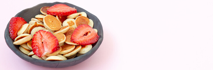 Mini cereal pancakes on a pink background.