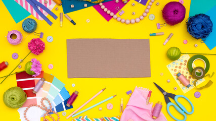 DIY. Multicolored craft supplies and tool on yellow background. Womens hobby - sewing, embroidery, felt craft, scrapbooking. Copy space.