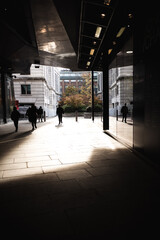 Silhouettes of people waking in a shopping centre on a bright sunny day