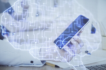 Double exposure of man's hand holding and using a digital device and brain hologram drawing. Data concept.