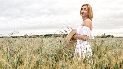 The girl in a delicate dress and hat. In a beautiful field. Gentle and beautiful.