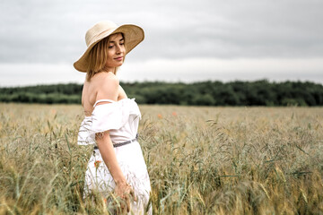 The girl in a delicate dress and hat. In a beautiful field. Gentle and beautiful.