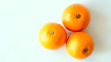 Plano cenital de tres frescas y coloridas naranjas para jugo totalmente aisladas en un fondo blanco con iluminación natural sobre ellas