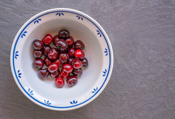 ceramic bowl with cherries over a slate floor