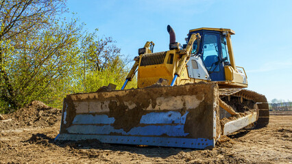 Heavy equipment machine wheel loader on construction jobsite. Close-up of bulldozer or excavator working with soil on highway.