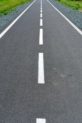 Perspective road marked with white dotted lines. Green grass along the way.