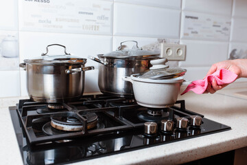 Utensils for cooking classes on stove in kitchen. Metal pans on kitchen counter. Female chef cooking in restaurant kitchen.