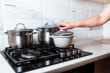 Utensils for cooking classes on stove in kitchen. Metal pans on kitchen counter. Female chef cooking in restaurant kitchen.