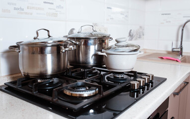 Utensils for cooking classes on stove in kitchen. Metal pans on kitchen counter. Female chef cooking in restaurant kitchen.