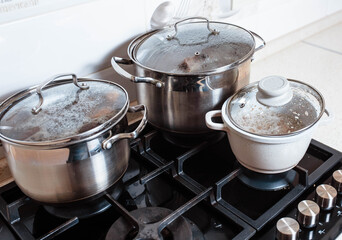Utensils for cooking classes on stove in kitchen. Metal pans on kitchen counter. Female chef cooking in restaurant kitchen.