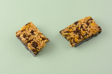 Dark chocolate and rice candy bar snack halves on light green background