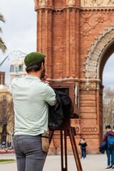 Young male photographer taking pictures using a vintage wooden camera at the Triumphal Arch in Barcelona