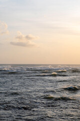 Many waves on the surface of the sea in windy weather at sunset.  Stormy sea and sunset sky