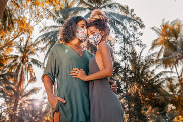 beautiful young couple wearing medical masks and gloves outdoors at sunset