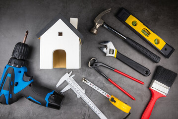 Wooden model white houses and Home Repair Hand Tools on a cement gray background. Concept home repair, Home improvement, Renovate home.