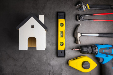 Wooden model white houses and Home Repair Hand Tools on a cement gray background. Concept home repair, Home improvement, Renovate home.