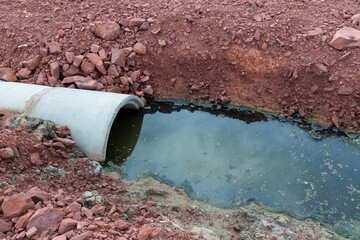Concrete circular run-off pipe discharging water. sewage pipe polluting the river. Sewage or...