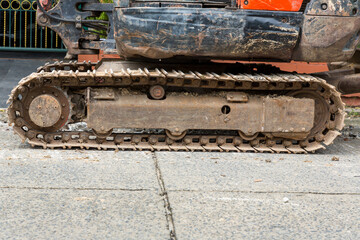 Fototapeta na wymiar Excavator tracks. Old iron caterpillars of the bulldozer of the tractor on the road. bulldozer caterpillar tracks. Black caterpillar tractor grader with the wheels on the ground.