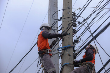 Electricians operate the electrical transmission system on the electricity pole.