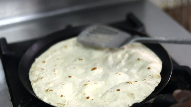 Cooking Indian bread parantha on a huge Indian pan at a street food restaurant. 