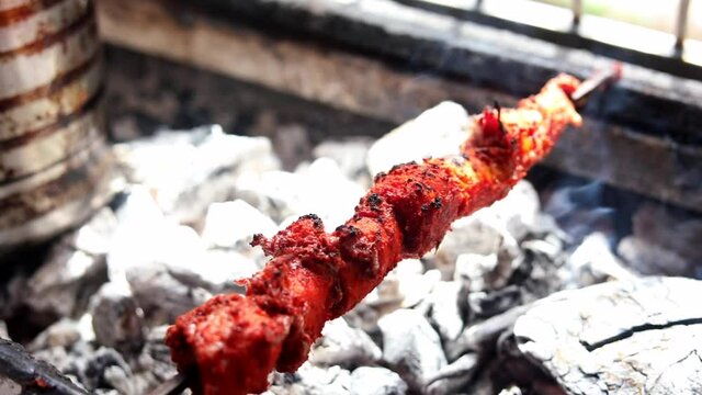 Making masala soya chaap tikka with onions and green mint chutney, served on a white plate.