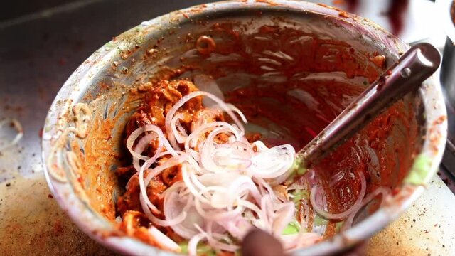 Making masala soya chaap tikka with onions and green mint chutney, served on a white plate.
