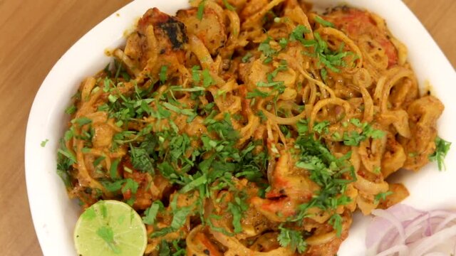 Making masala soya chaap tikka with onions and green mint chutney, served on a white plate.