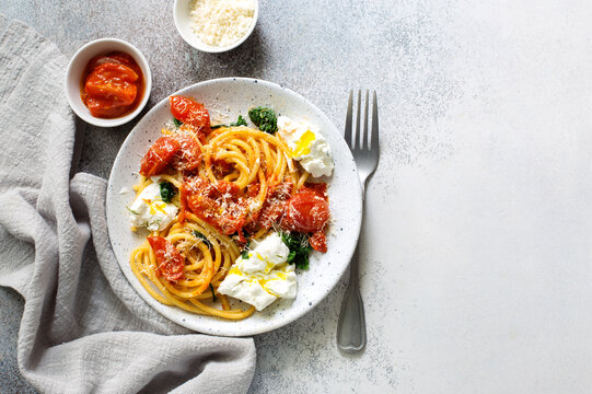 Pasta bucatini with tomato sauce, tomatoes, spinach soft cheese and parmesan cheese