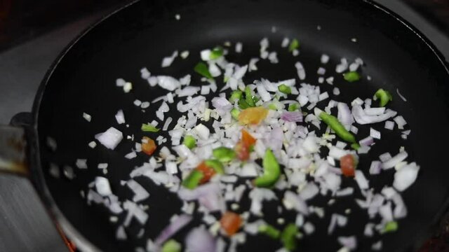 Cooking red sauce, with sauteed vegetables, caramelised onions, red chillies and capsicum on a hot oil pan.
