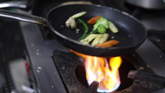 Cooking red sauce, with sauteed vegetables, caramelised onions, red chillies and capsicum on a hot oil pan.