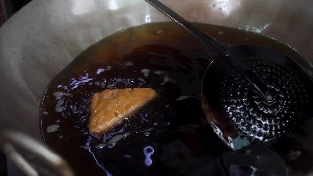 Making indian style fritters or bread pakoda by deep frying vegetables stuffed marinated bread in hot oil kadhai.