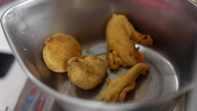 Making indian style fritters or bread pakoda by deep frying vegetables stuffed marinated bread in hot oil kadhai.