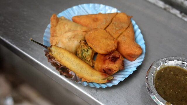Making indian style fritters or bread pakoda by deep frying vegetables stuffed marinated bread in hot oil kadhai.