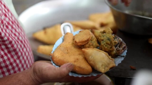 Making indian style fritters or bread pakoda by deep frying vegetables stuffed marinated bread in hot oil kadhai.
