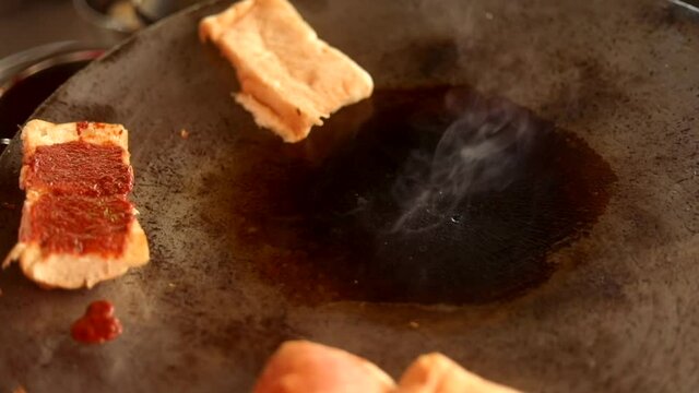 Making indian street vada pav on a fry pan served with green chutney, red tomato sauce and masala.