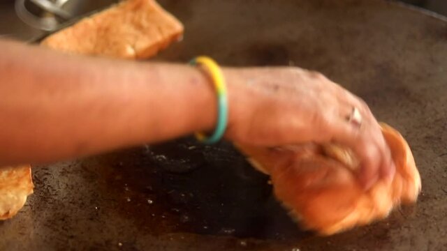 Making indian street vada pav on a fry pan served with green chutney, red tomato sauce and masala.