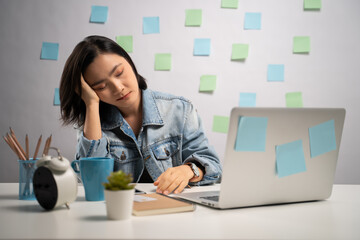 Asian woman working on a laptop tired and take a nap at home office. WFH. Work from home. Prevention Coronavirus COVID-19 concept.