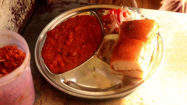 Making indian style street chaat and raj kachori with topped spices, red sauce and corns. 